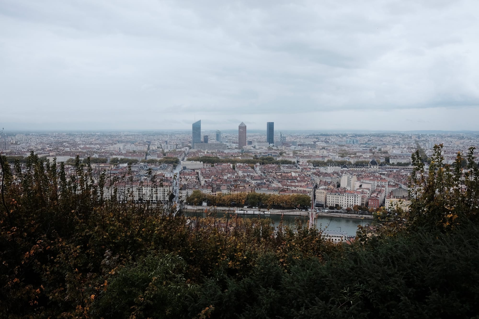 Lyon, viewed from Notre-Dame de Fourvière: older red-roofed buildings in the foreground and modern towers behind them.