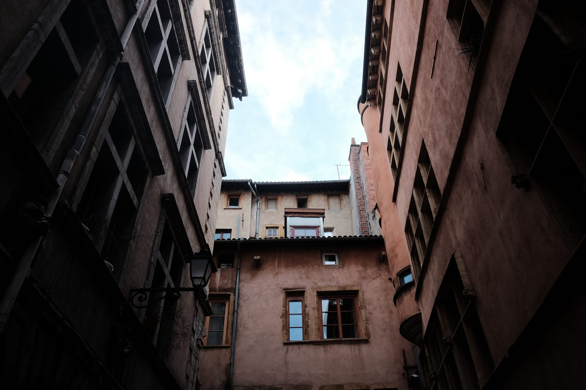 A courtyard in Lyon surrounded by buildings with terracotta-coloured render.