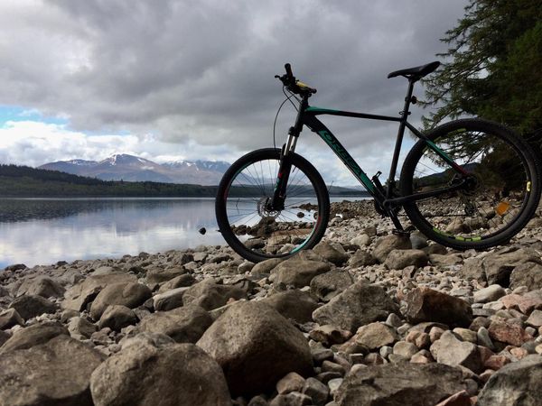 A mountain bike stands on the loch side with Ben Nevis in the background.