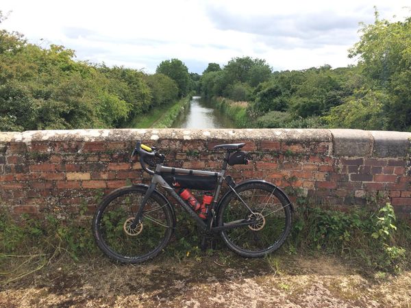 A gravel bike on a rural canal bridge.